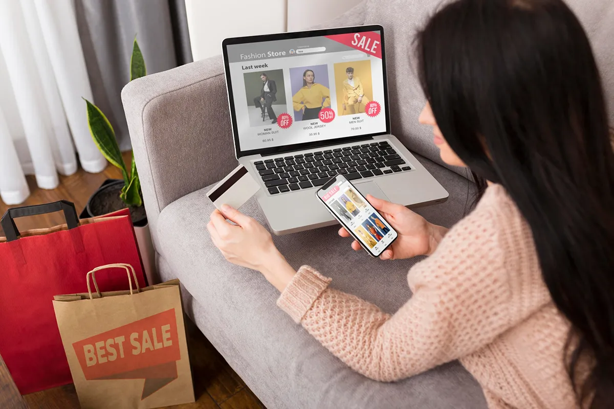 An online shopper using a smartphone and a laptop to make a purchase