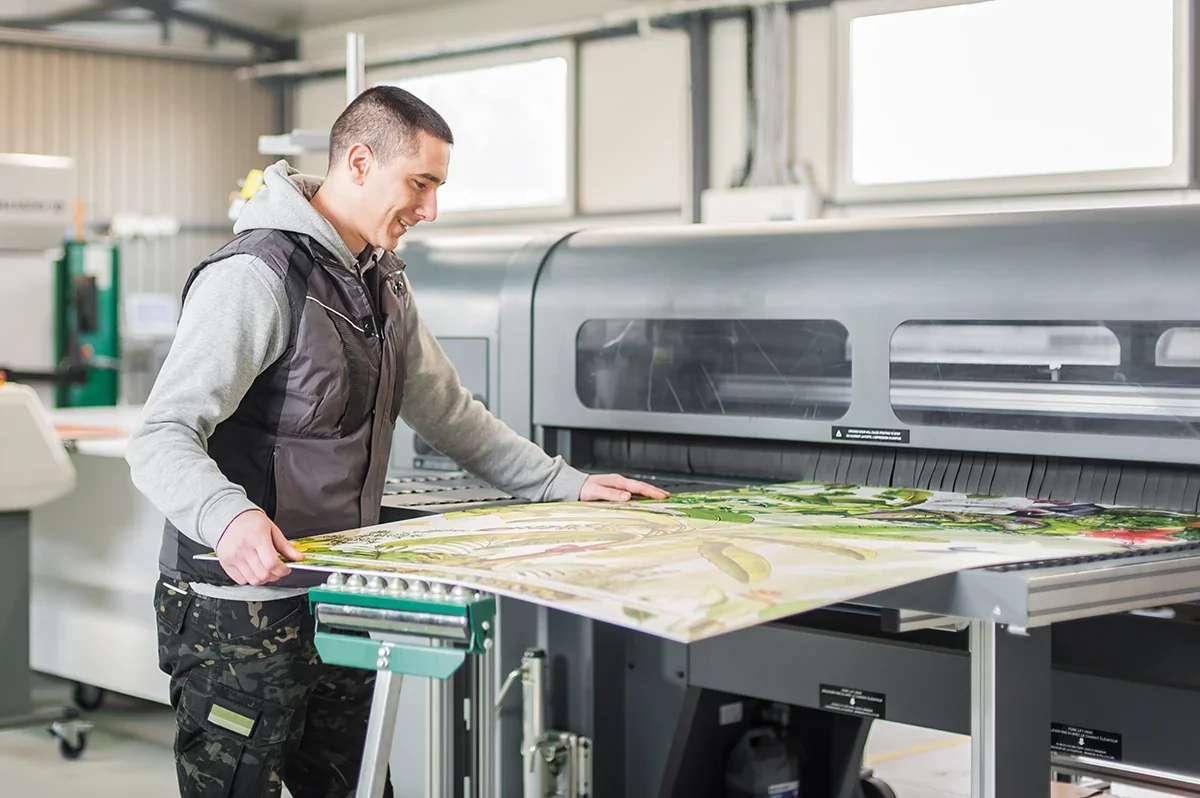A print technician operating a large-format printer