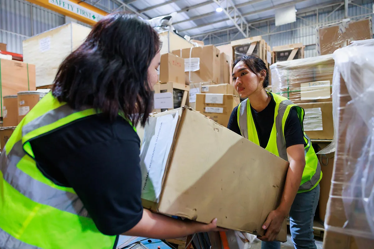 Warehouse staff moving inventory boxes as part of logistics and fulfillment operations.