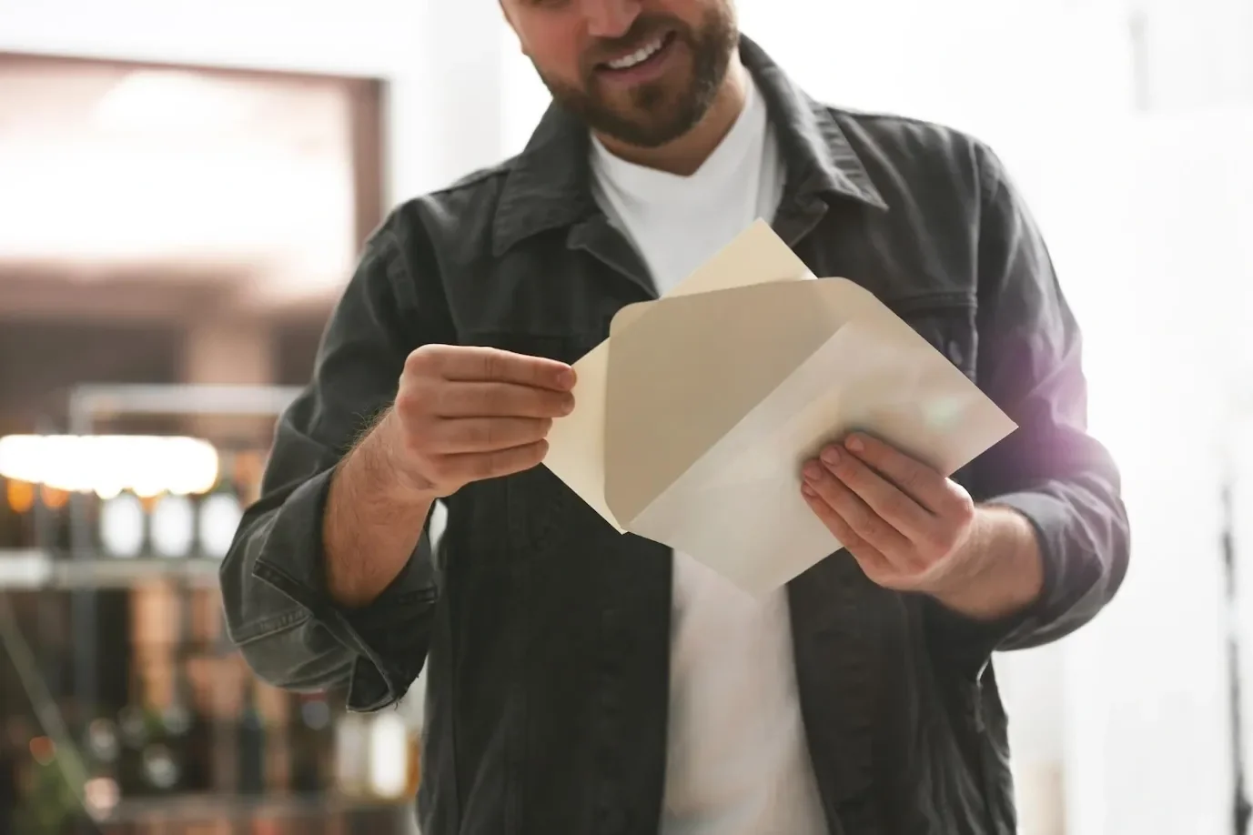 Smiling man opening a cream envelope, showing how direct mail adds a personal touch to digital campaigns
