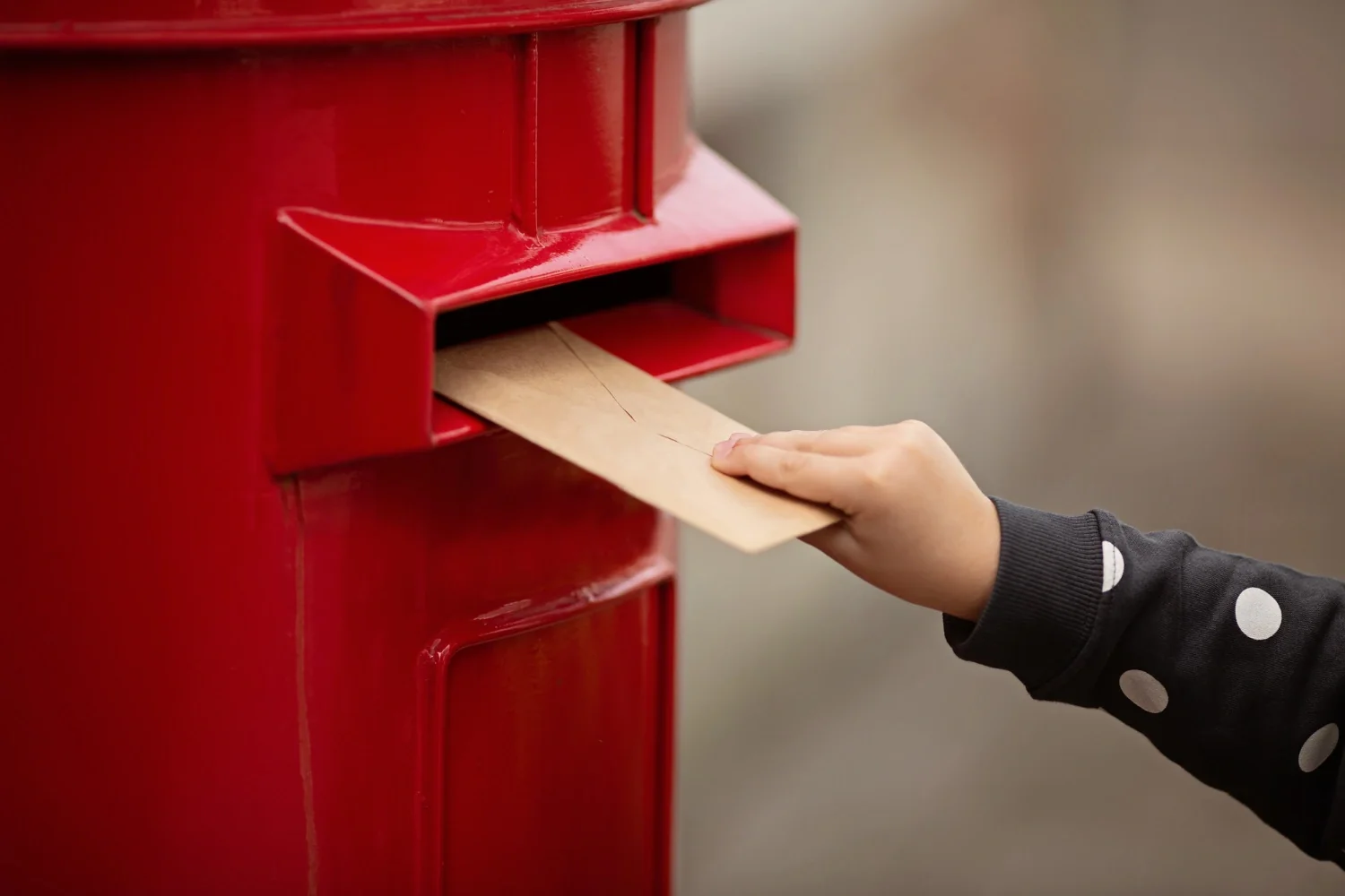 Hand dropping a direct mail piece into a mailbox, representing personalized print campaigns