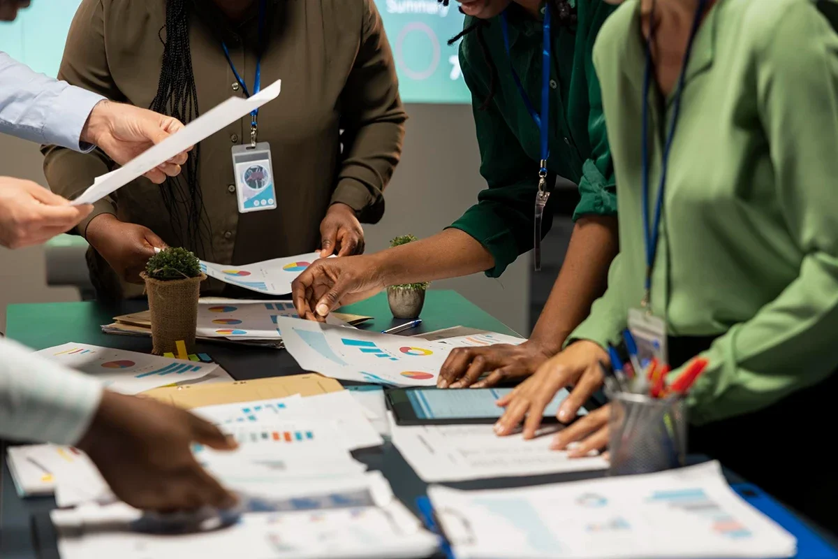 Marketing team reviewing printed charts and reports during a live event planning session.