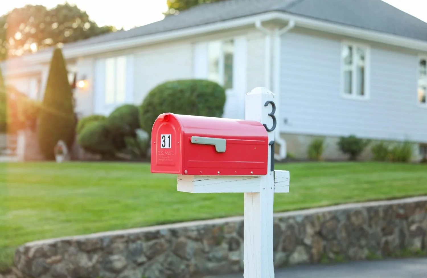 Red mailbox in front of a suburban home, representing where realtor postcards land with homeowners