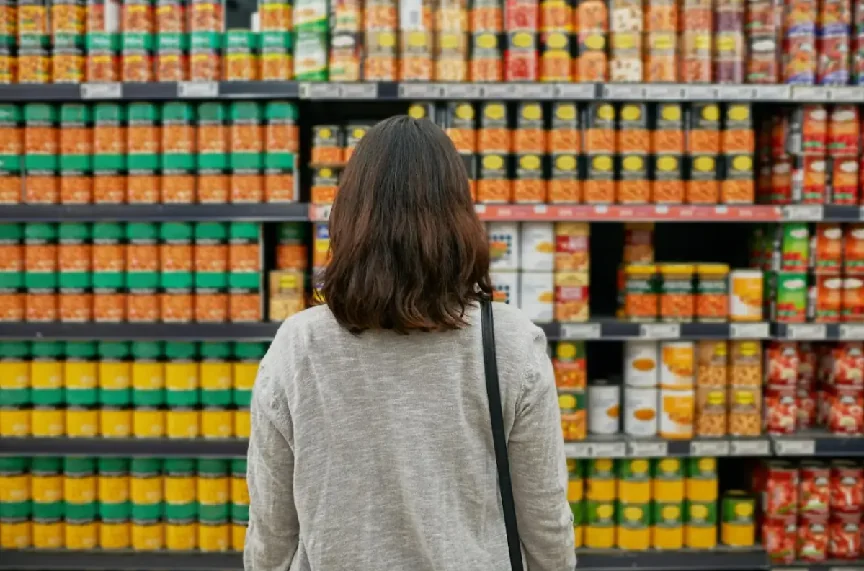 A woman standing in front of a retail shelf stocked with CPG products, highlighting the importance of standout packaging design for small brands